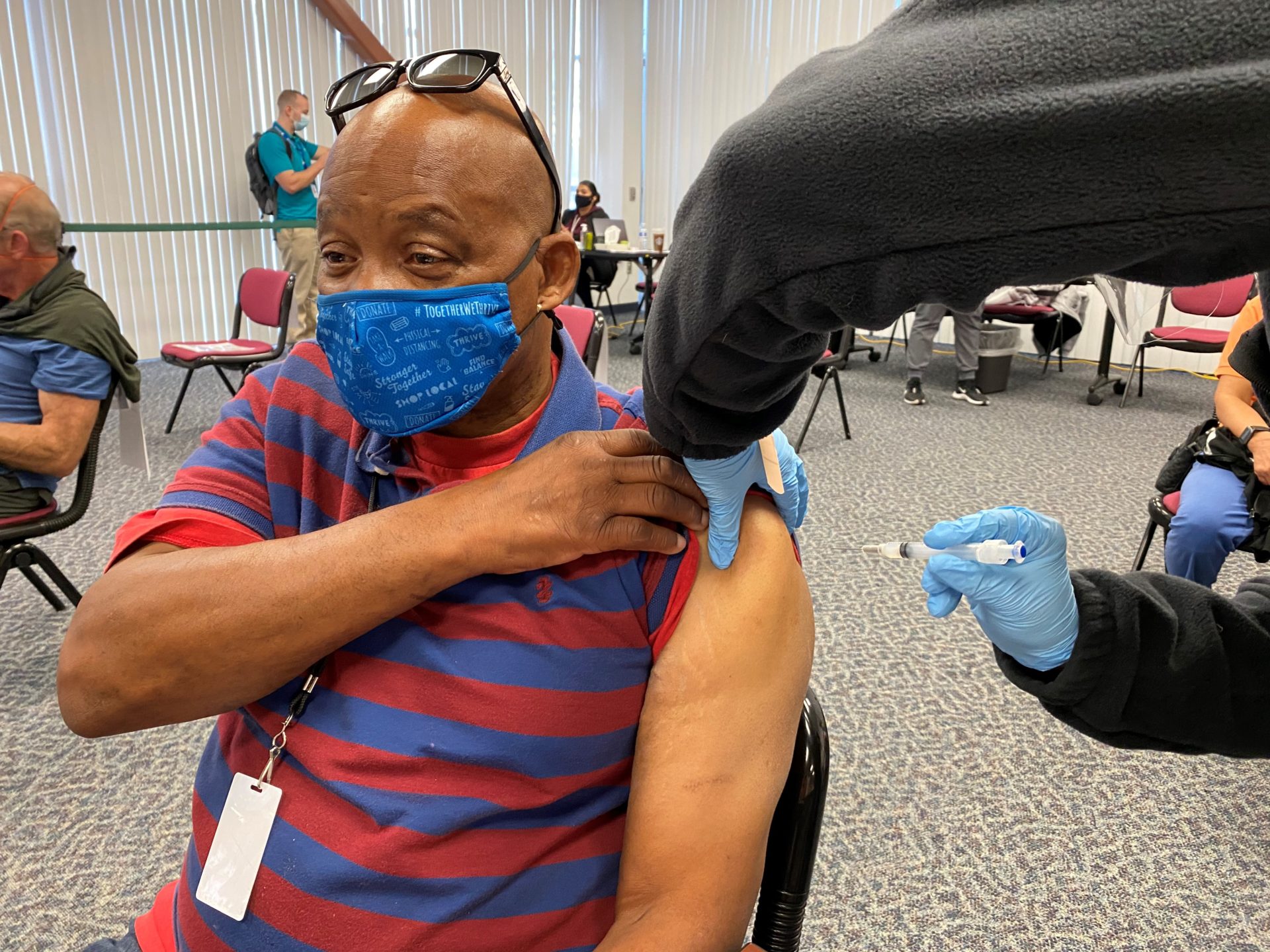 man wearing a mask gets a vaccination in his arm