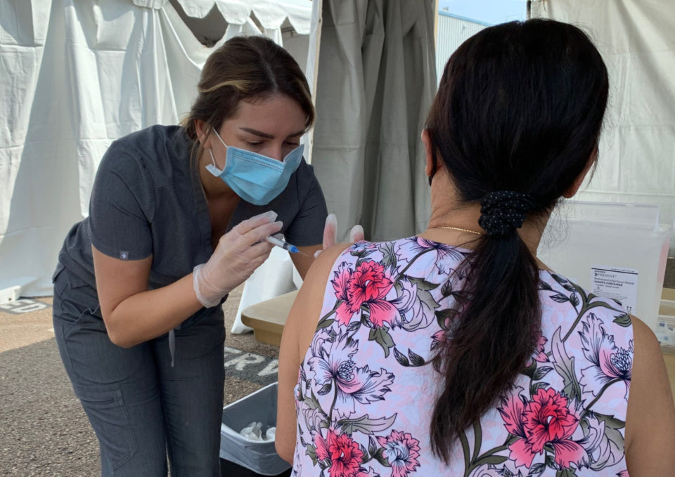 a medical professional gives a flu shot to a woman