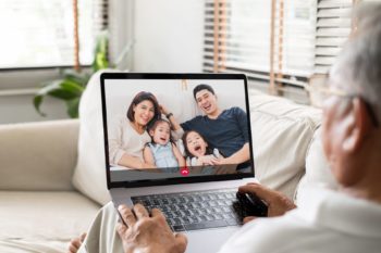 man sits with laptop on his lap talking to family