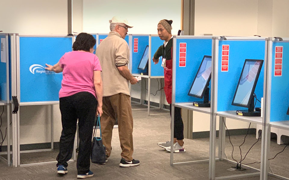 two people near ballot marking devices