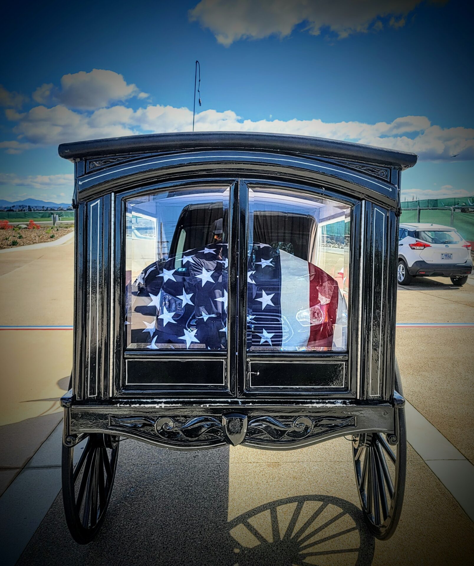 Casket covered by flag in horse drawn carriage