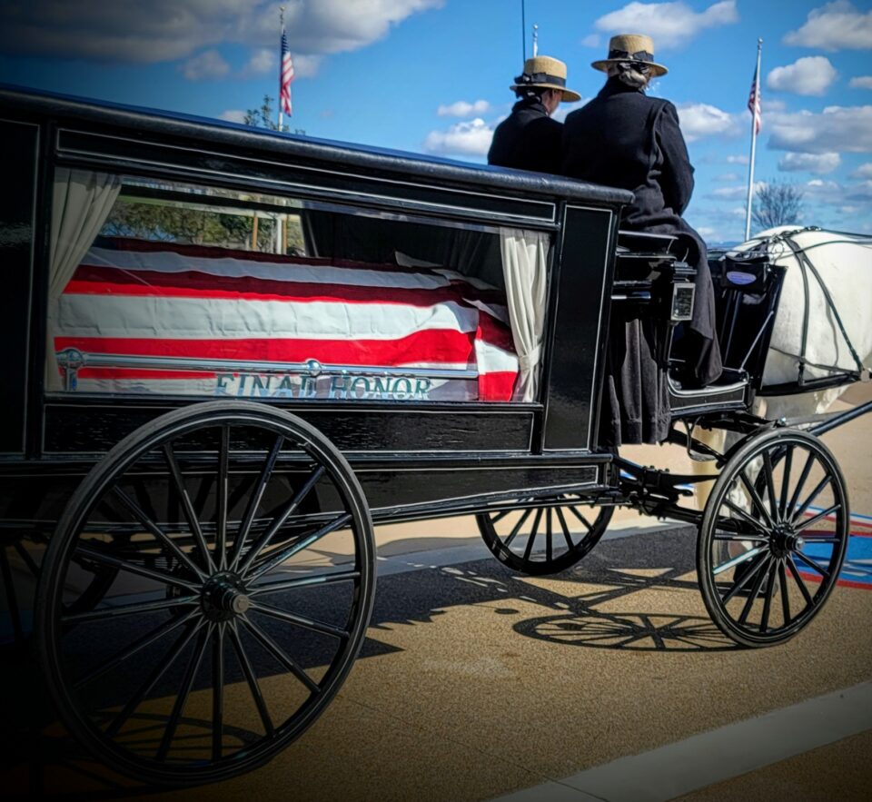 horse drawn carriage with casket covered in American flag