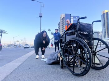 Outreach worker bends down and speaks with man experiencing homelessness