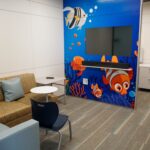 a room with a TV on the wall and mural of fish