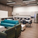 a room with seating, tables and a kitchen