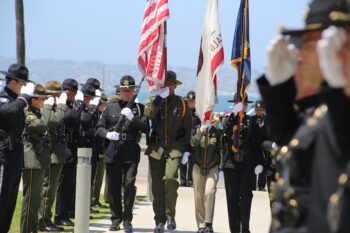 law enforcement stand at salute as flags are carried by