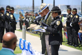 3 uniformed officers each hold a hat during the ceremony
