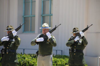 3 uniformed officers hold rifles aimed in the sky
