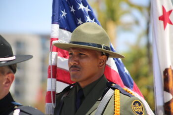 A US Border Patrol officer stands in front of a flag