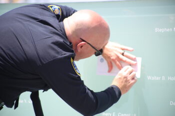an uniformed officer traces a name engraved on the Law Enforcement memorial