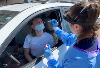 a young woman is being tested for coronavirus while inside her car