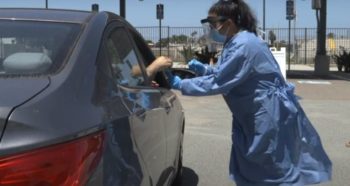 a nurse assisting someone inside a car at a testing facility