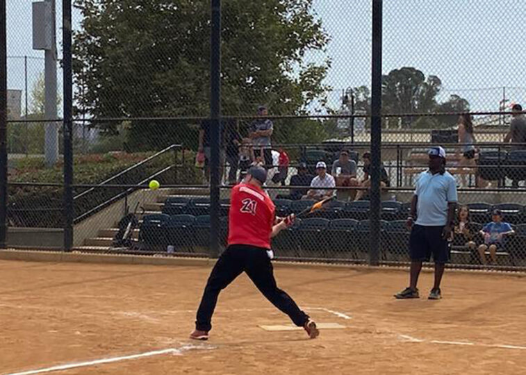 Softball game with someone about to hit a ball.