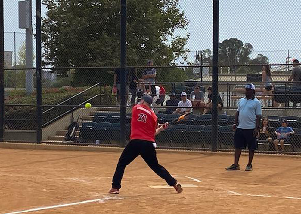 Softball game with someone about to hit a ball.