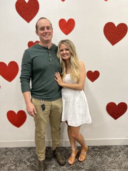 couple stands in front of wall with hearts