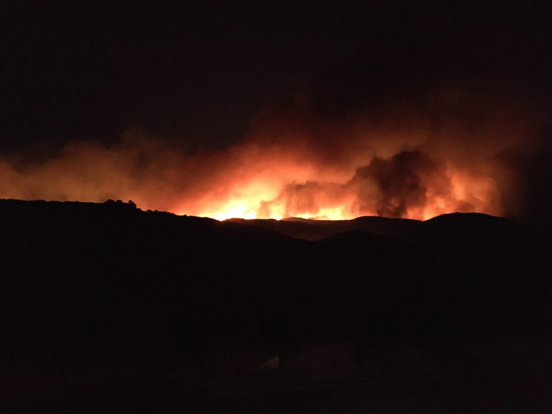 Photo of fire flames on a ridge at night.