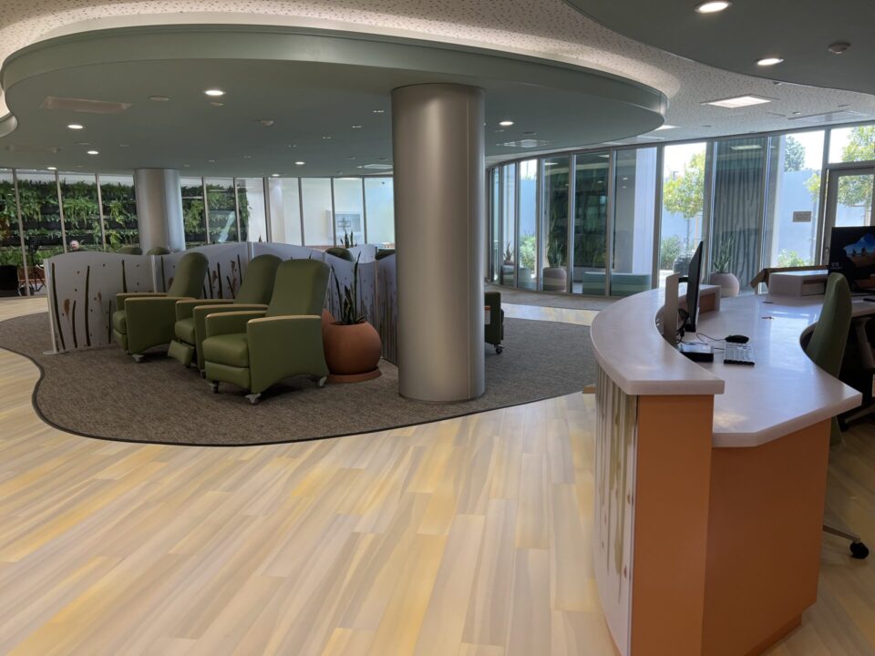 inside of the Oceanside Crisis Stabilization Unit. It has a desk and some comfortable chairs for clients. The room is furnished in soothing tones and windows to contribute to a calm vibe.