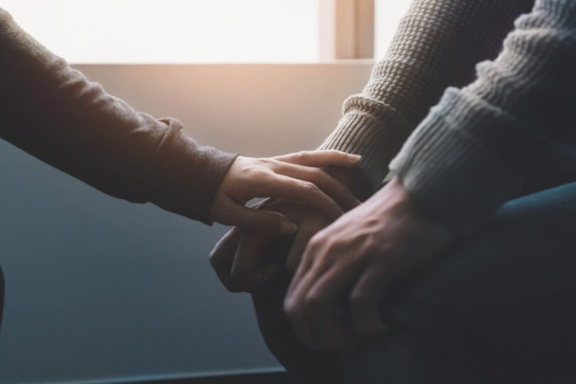 a hand rest on another person's hand