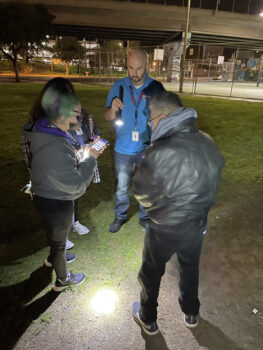 four people standing near an overpass speak to each other in a circle