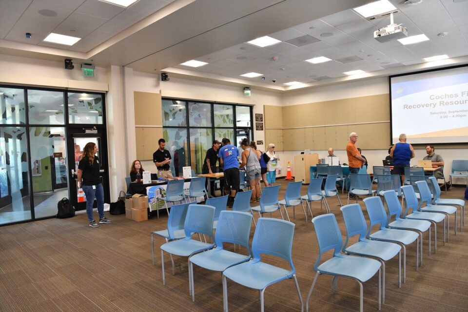 People standing and speaking in front of tables in a room at the Lakeside Library