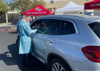 An EMT approaches the vehicle of a Ramona resident scheduled to get the COVID vaccine.