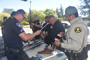 a group of law enforcement officers at a table with weapons