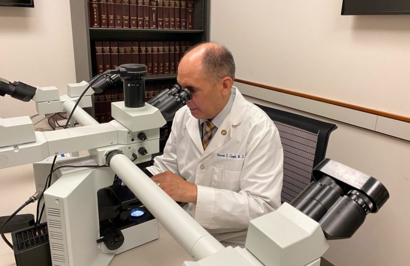 Forensic investigator looks in microscope.