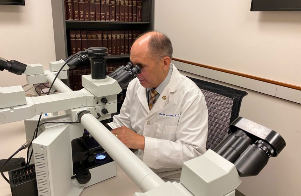 Forensic investigator looks in microscope.