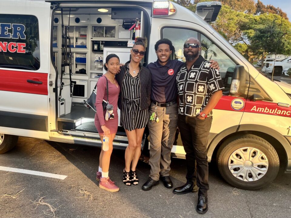 Family of four pose in front of ambulance
