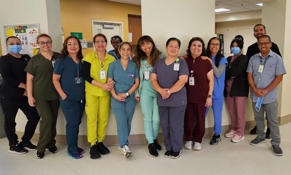 group wearing medical scrubs stands in front of work station