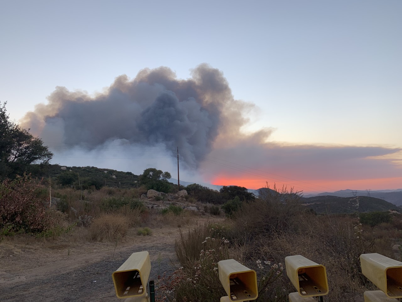 Smoke plume rising and orange glow from fire on ridge