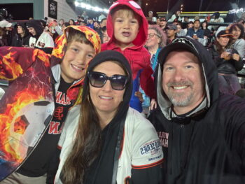 Man, wife, 2 kids in stands at a ball game