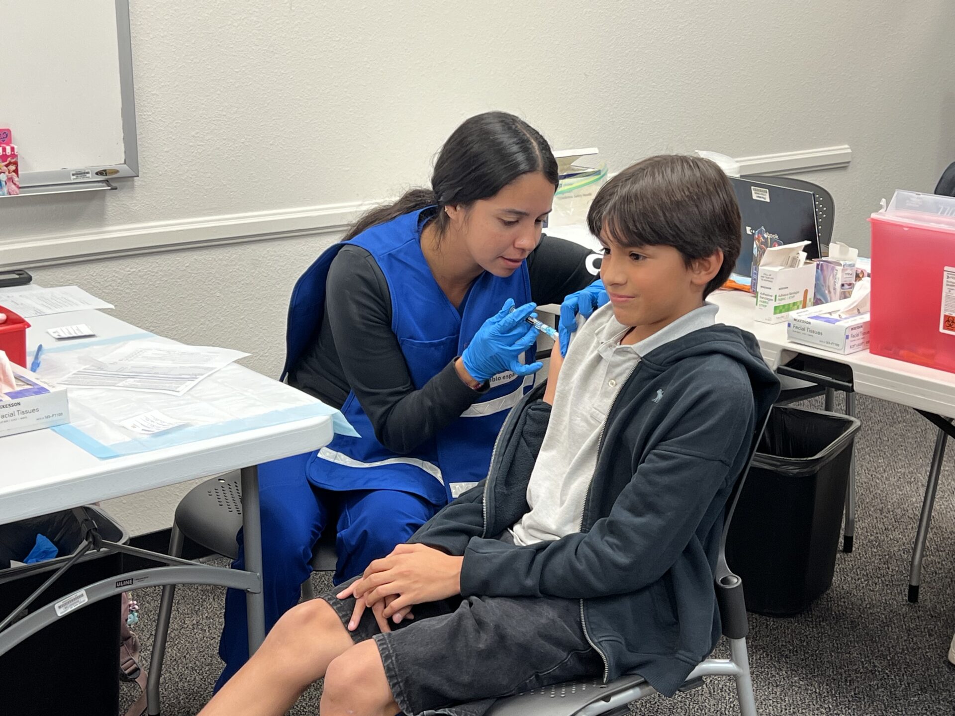 person giving a adolescent a vaccine in his arm