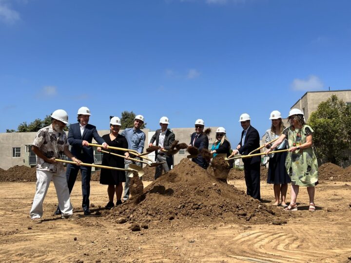 people standing around a pile of soil with shovels