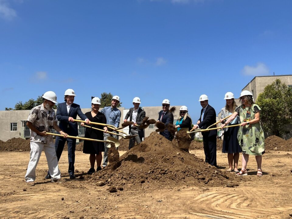 people standing around a pile of soil with shovels
