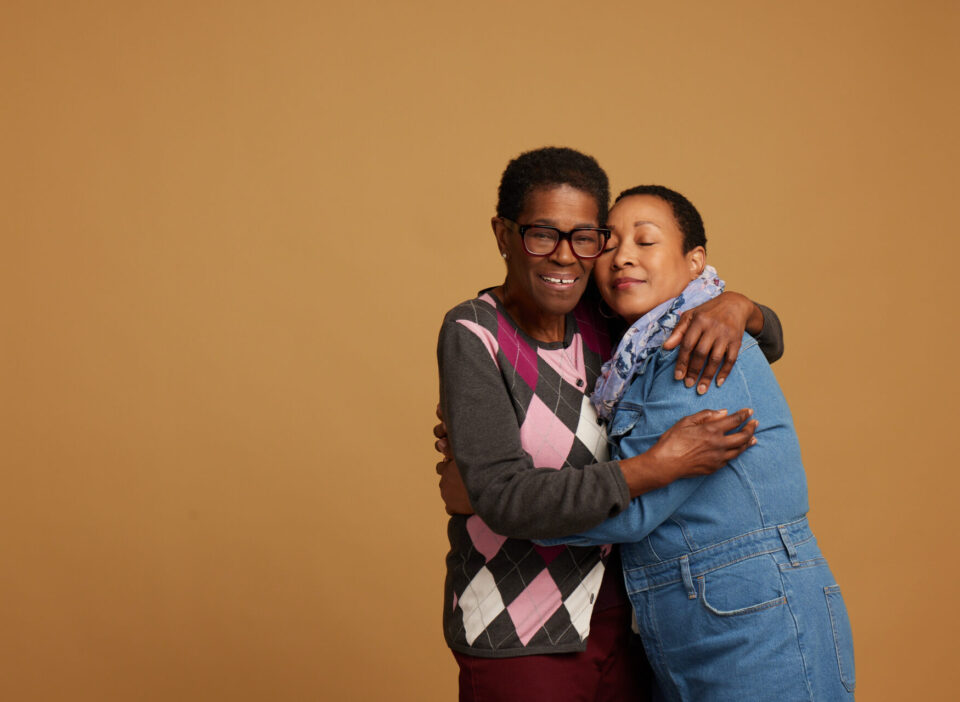 Two people embrace. Yellow backdrop.