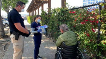 two people talk to a man in a wheelchair