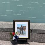Photo of fallen officer in front of memorial wall
