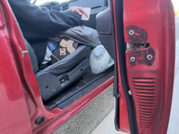 a person sits in a car and holds a gift card