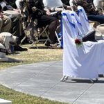 Hats of fallen officers on chairs in front of memorial wall