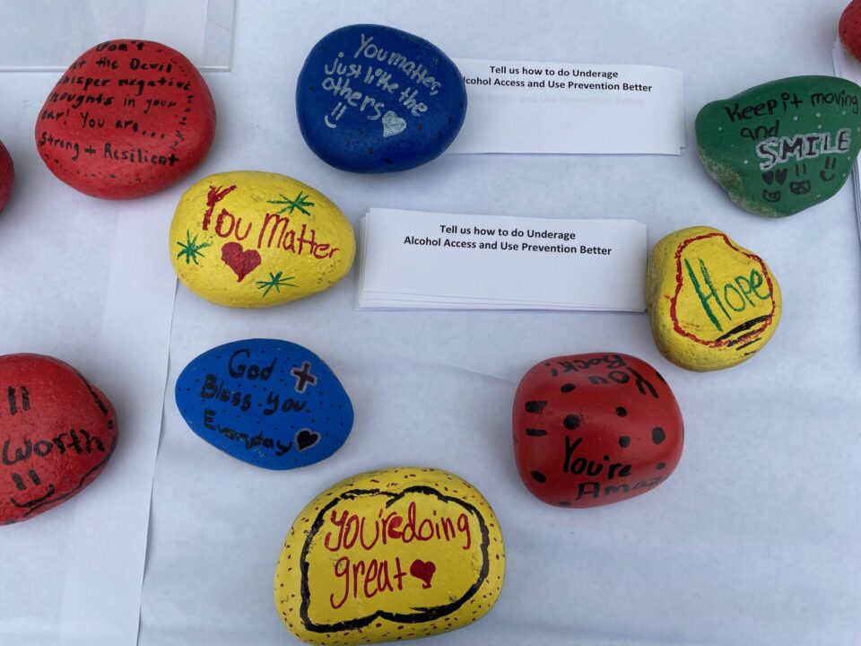 Rocks on table painted in blue, red and yellow with inspirational messages of hope