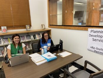 Two people smile at a desk