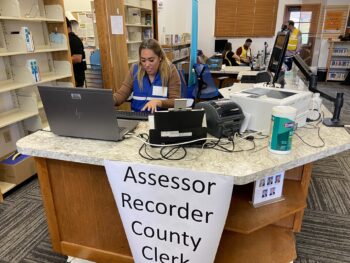 A person sits at a counter from the Assessor/Recorder/County Clerk