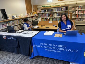 A person sits at a computer at table hosted by the Assessor/Recorder/County Clerk