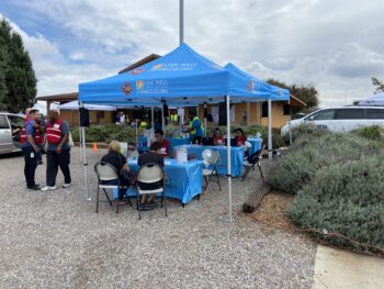 Two people sit at a Live Well San Diego pop-up tent