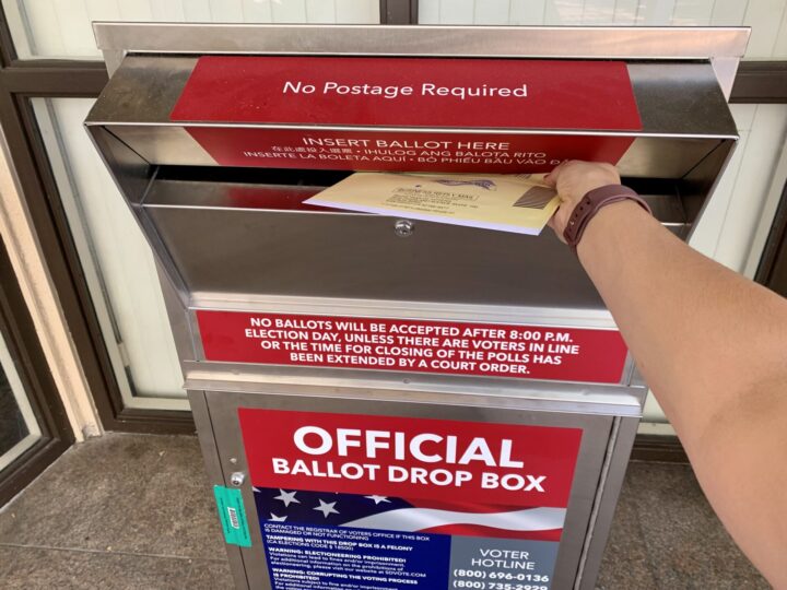 Person mailing ballot in ballot drop box.