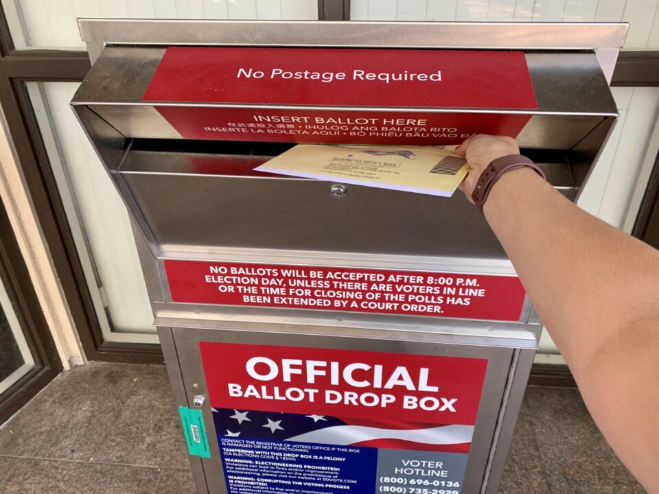 Person mailing ballot in ballot drop box.