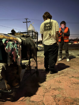 a volunteer speaks to a person standing next to filled shopping cart