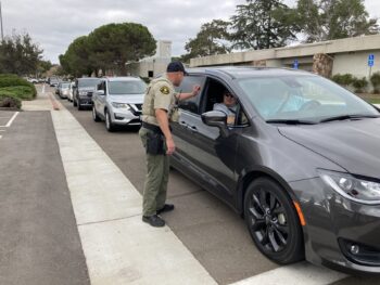 a line up of cars with a deputy speaking to occupants of the first car