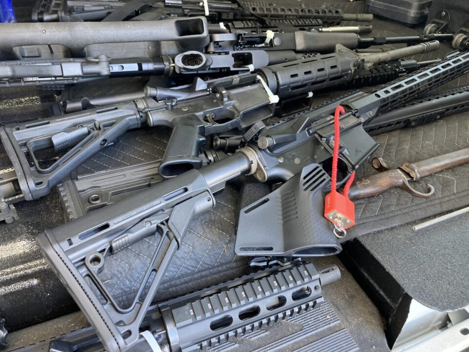 Black assault rifles turned in for gift cards on a table